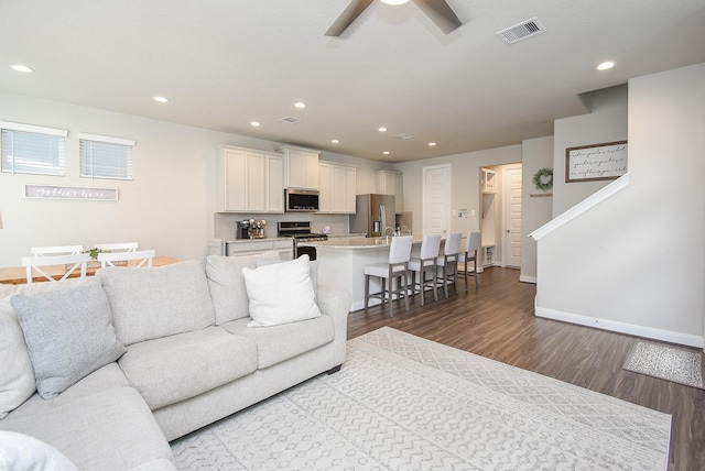 living room featuring ceiling fan and dark hardwood / wood-style floors