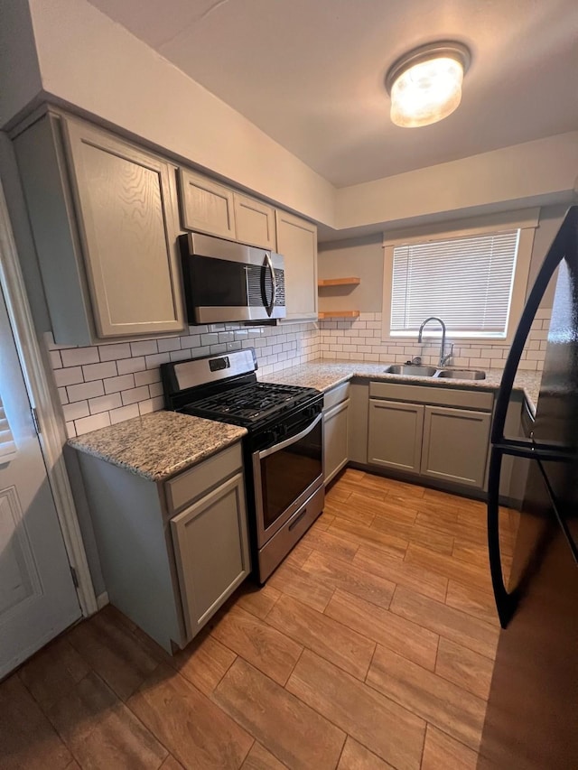 kitchen with gray cabinetry, light hardwood / wood-style floors, sink, and stainless steel appliances