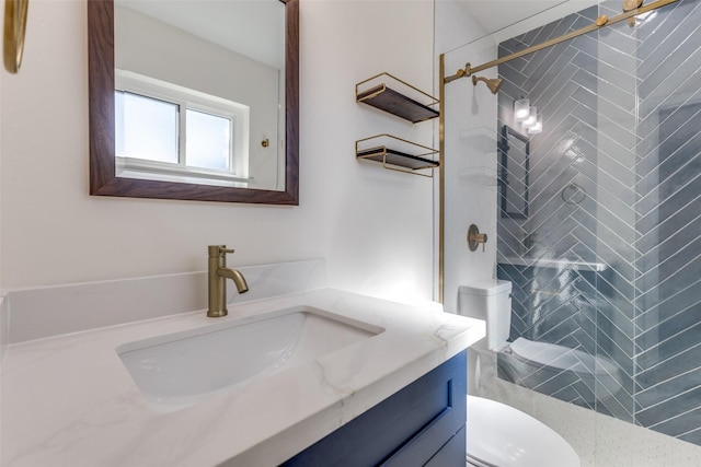 bathroom featuring toilet, vanity, and tiled shower