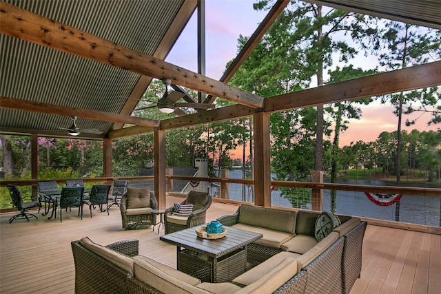 deck at dusk with an outdoor hangout area, a water view, and ceiling fan