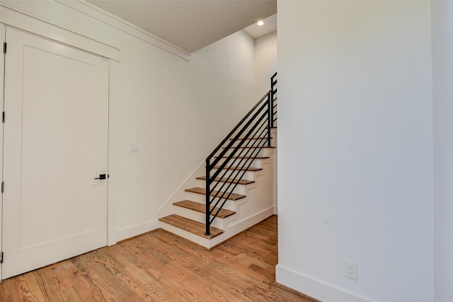 stairway with crown molding and hardwood / wood-style floors