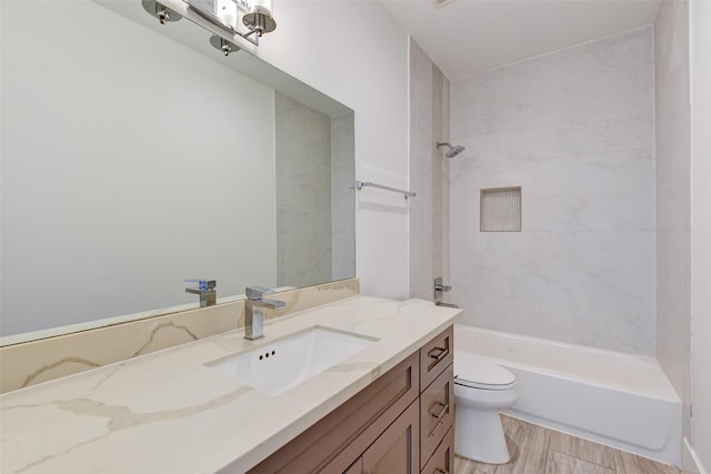 full bathroom featuring vanity, tiled shower / bath combo, and toilet