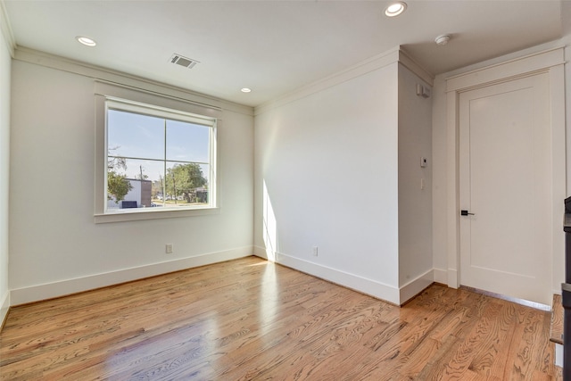 empty room with crown molding and light hardwood / wood-style flooring