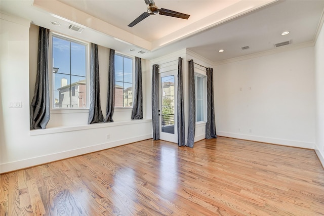 spare room with ceiling fan, a raised ceiling, crown molding, and light hardwood / wood-style flooring