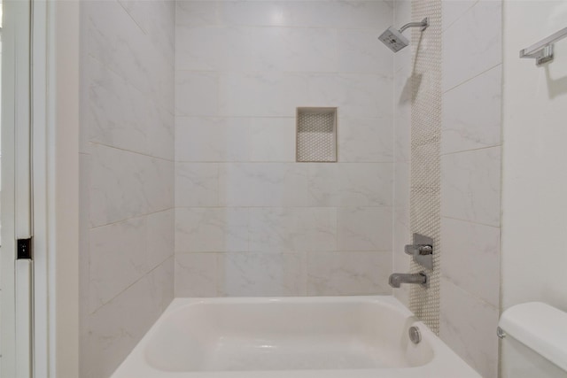 bathroom featuring tiled shower / bath combo and toilet