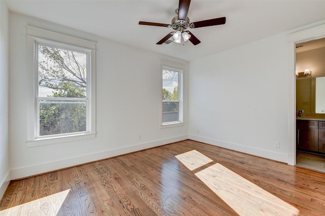 empty room with light hardwood / wood-style floors, a wealth of natural light, and ceiling fan