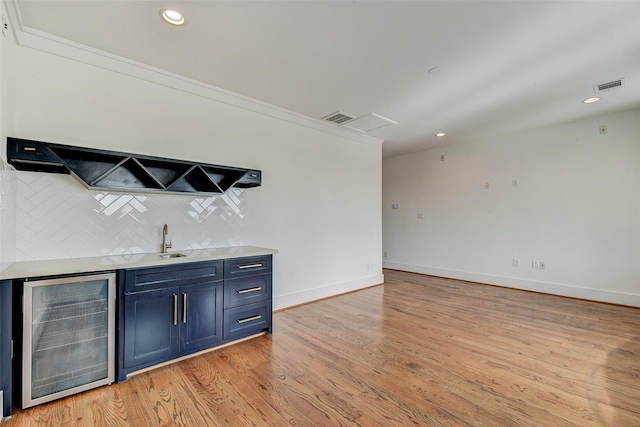 bar with decorative backsplash, light hardwood / wood-style floors, crown molding, and beverage cooler