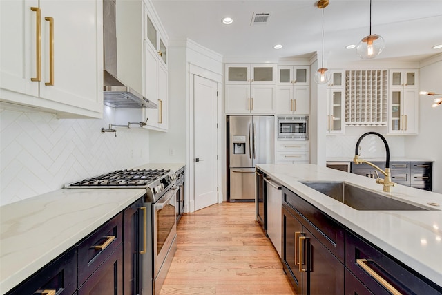 kitchen with backsplash, sink, stainless steel appliances, and wall chimney range hood