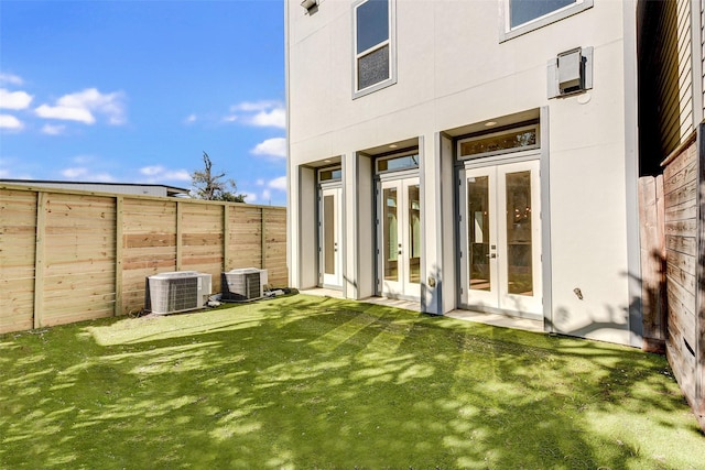 exterior space with a lawn, central AC, and french doors