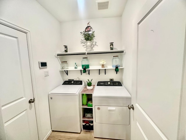 laundry area featuring separate washer and dryer and light hardwood / wood-style floors