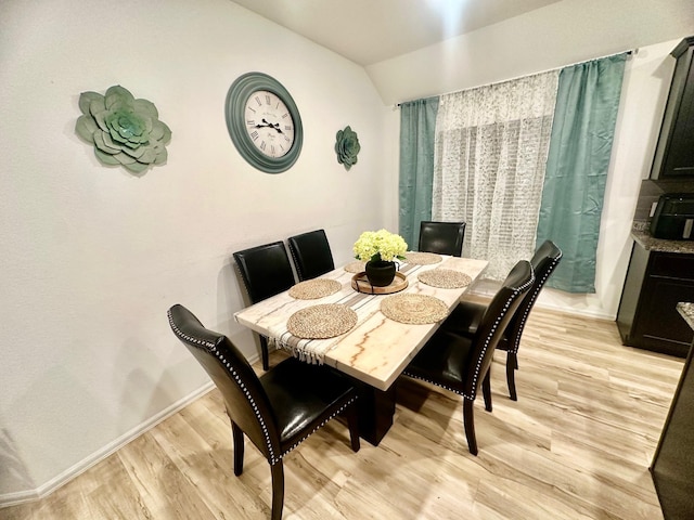 dining space featuring light wood-type flooring and lofted ceiling