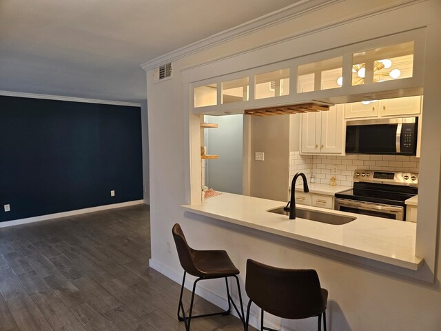 kitchen with sink, crown molding, stainless steel appliances, white cabinets, and decorative backsplash