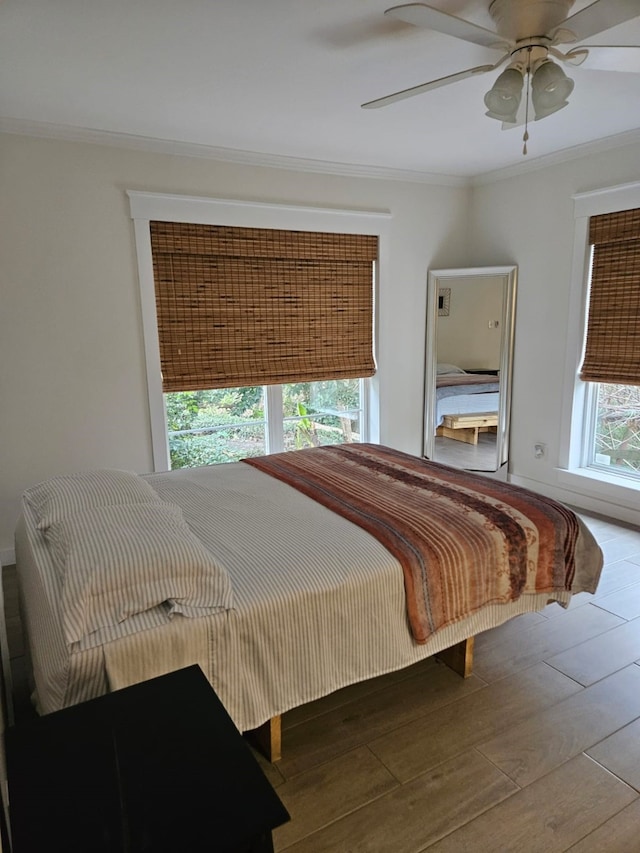 bedroom featuring hardwood / wood-style floors, ornamental molding, and ceiling fan