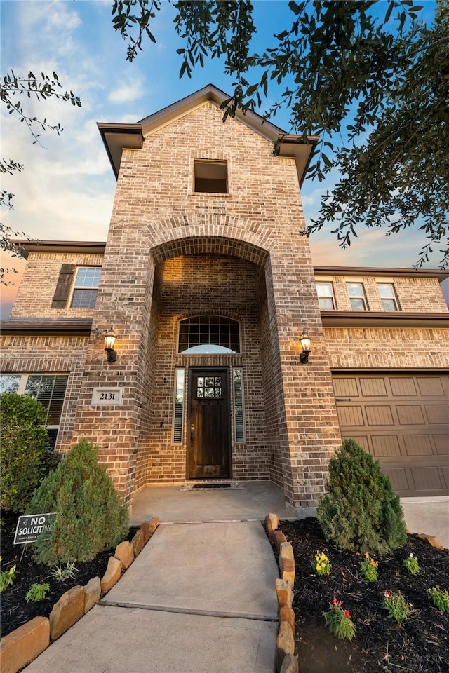 exterior entry at dusk featuring a garage