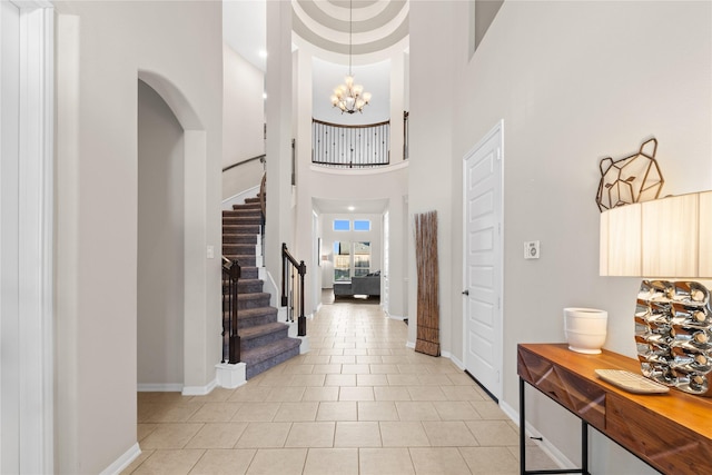 entrance foyer featuring light tile patterned flooring, a towering ceiling, and a chandelier