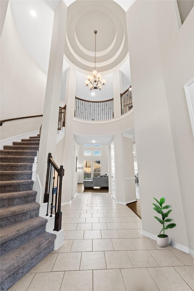 tiled foyer with a notable chandelier, a raised ceiling, and a high ceiling