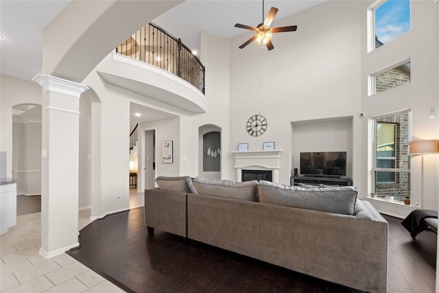 living room featuring ceiling fan, light hardwood / wood-style floors, and a high ceiling