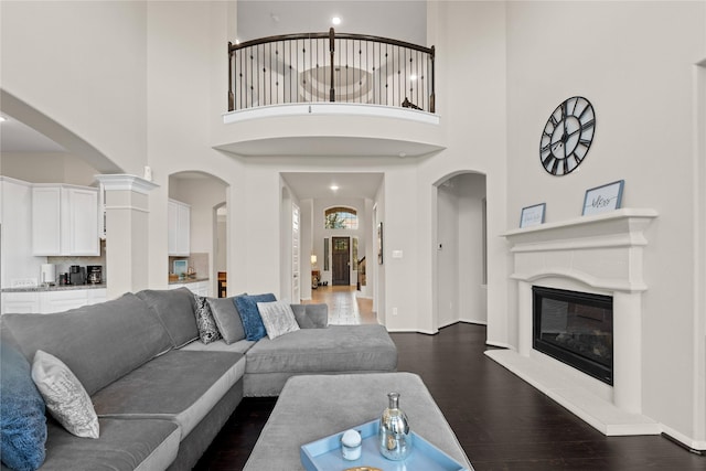 living room with a towering ceiling and dark wood-type flooring