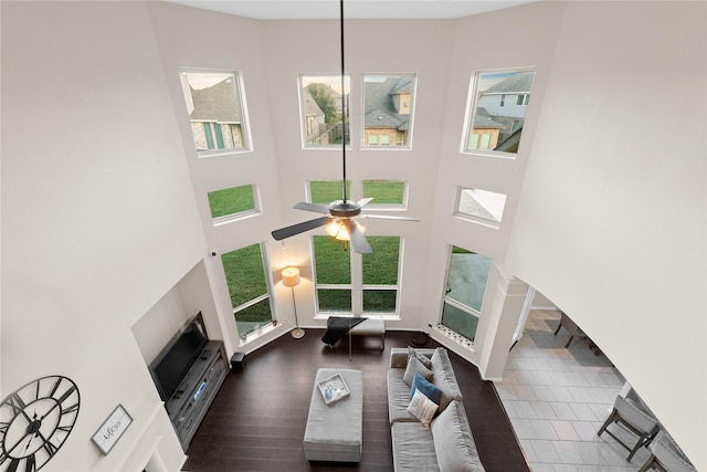 living room with ceiling fan, dark wood-type flooring, and a high ceiling