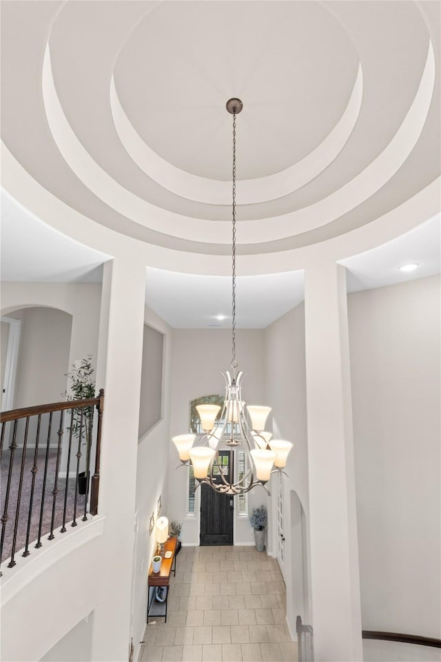 interior space with a raised ceiling and a notable chandelier