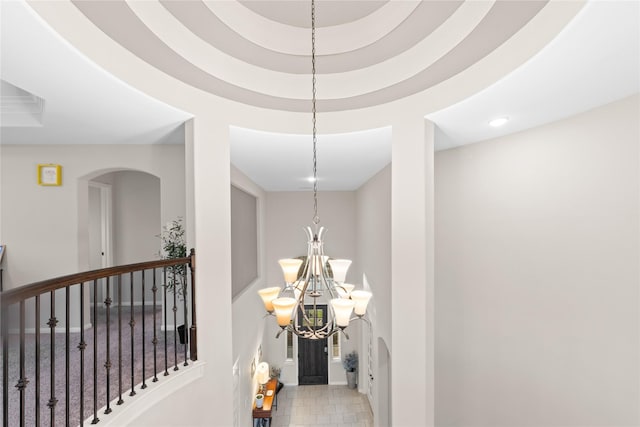 hallway with a raised ceiling and an inviting chandelier