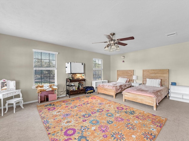 bedroom with ceiling fan, carpet floors, and multiple windows