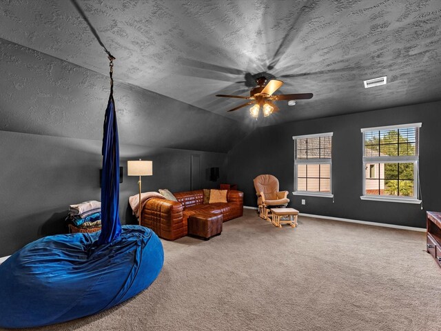 interior space with a textured ceiling, ceiling fan, carpet floors, and lofted ceiling