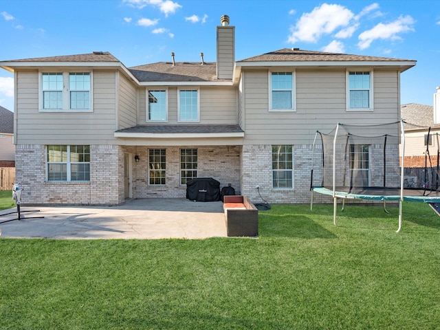 back of house featuring a lawn, a patio area, and a trampoline