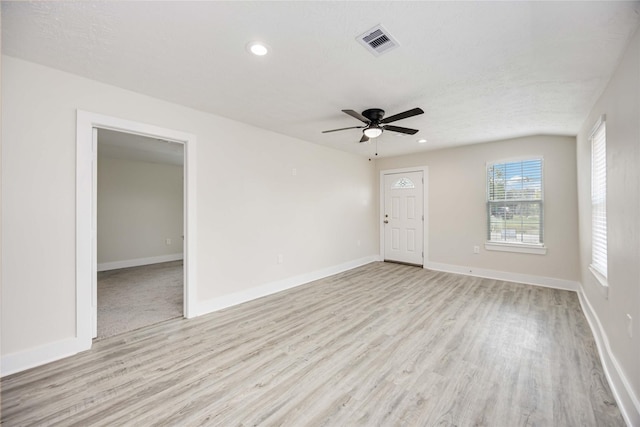 unfurnished room with a textured ceiling, light wood-type flooring, and ceiling fan