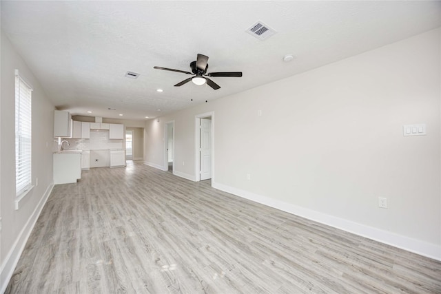 unfurnished living room featuring a textured ceiling, light hardwood / wood-style flooring, plenty of natural light, and ceiling fan