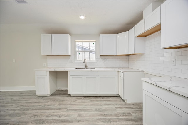 kitchen with white cabinets, light wood-type flooring, and sink