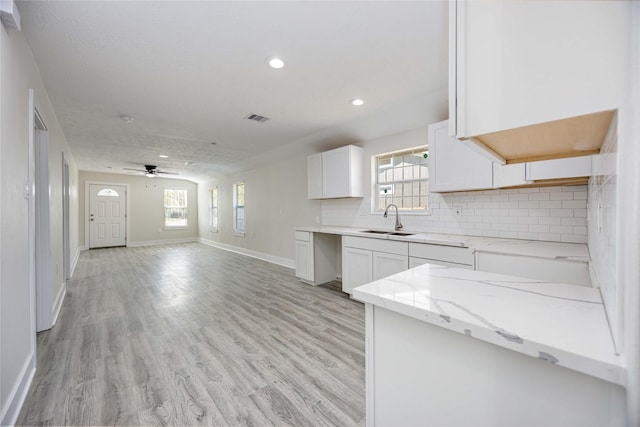 kitchen featuring white cabinetry, sink, ceiling fan, light stone counters, and light hardwood / wood-style floors