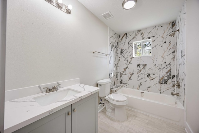 full bathroom with toilet, vanity, and tiled shower / bath