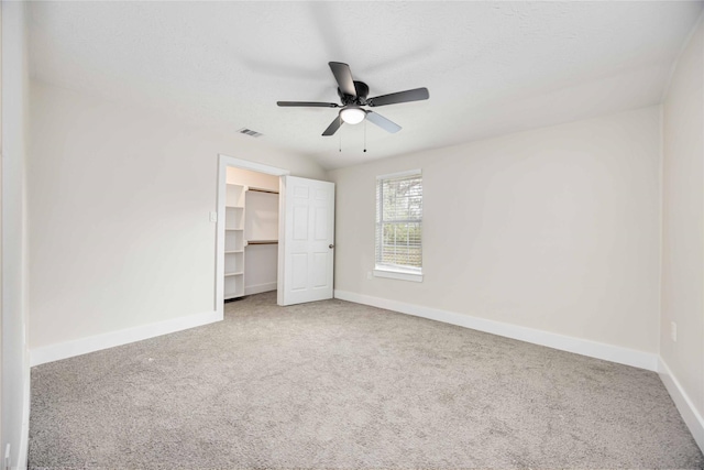 unfurnished bedroom featuring carpet floors, a closet, a spacious closet, and ceiling fan