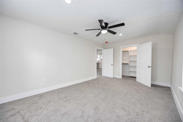 unfurnished bedroom featuring carpet flooring, ceiling fan, a textured ceiling, a walk in closet, and a closet