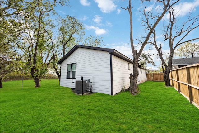 back of house featuring central AC unit and a lawn