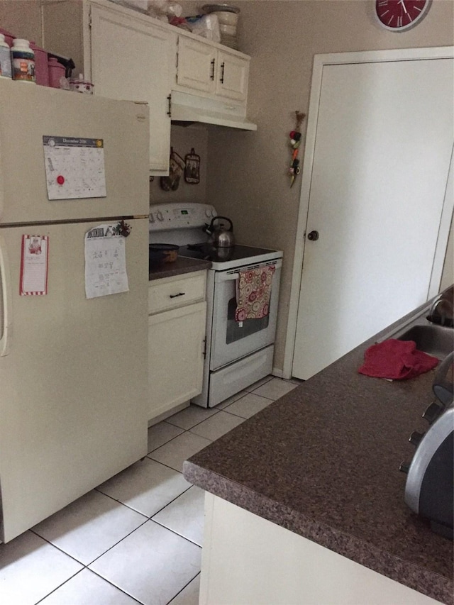 kitchen with light tile patterned floors, white appliances, and white cabinets