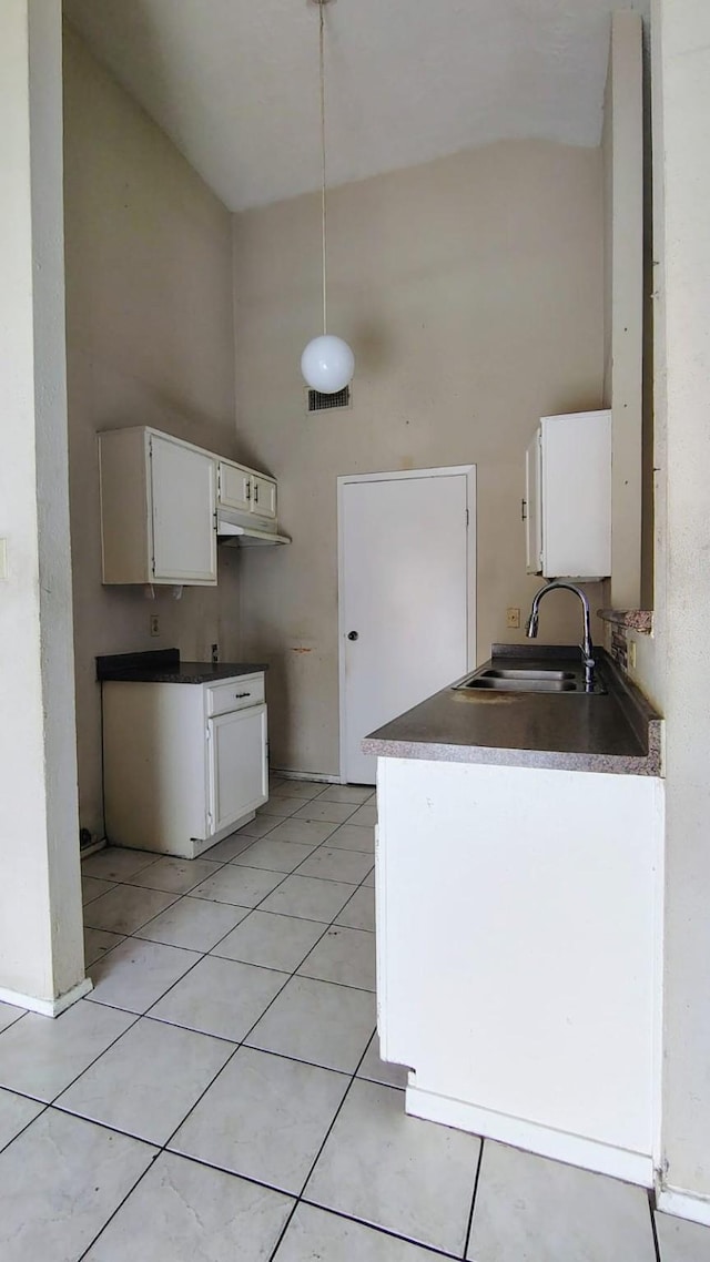 kitchen with sink, white cabinetry, light tile patterned floors, and a towering ceiling