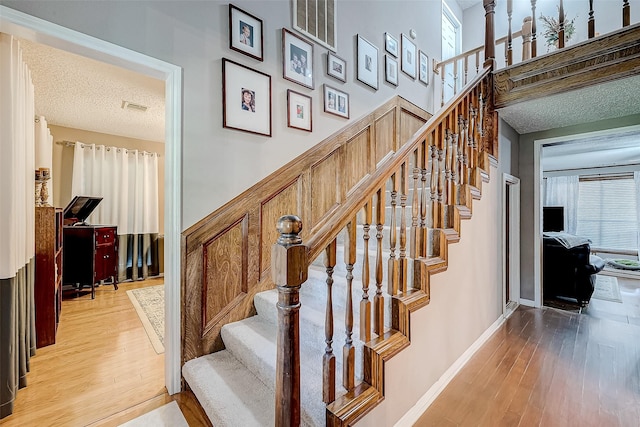 stairs featuring wood-type flooring and a textured ceiling