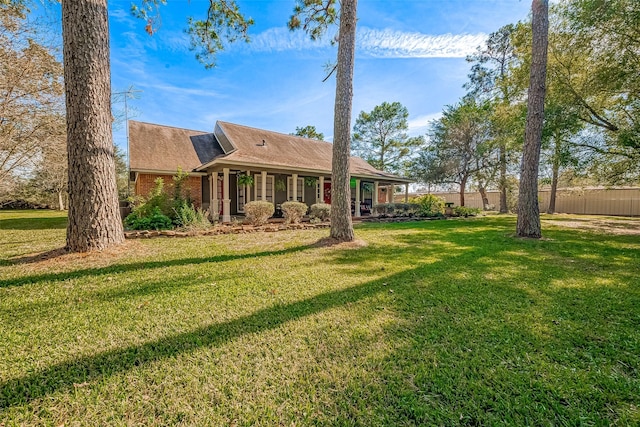 rear view of property with brick siding, a yard, and fence