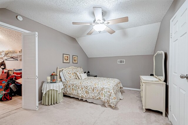 bedroom with light carpet, a closet, ceiling fan, and a textured ceiling