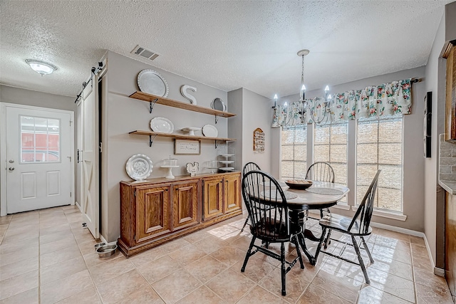 dining room featuring a notable chandelier, a healthy amount of sunlight, a barn door, and a textured ceiling