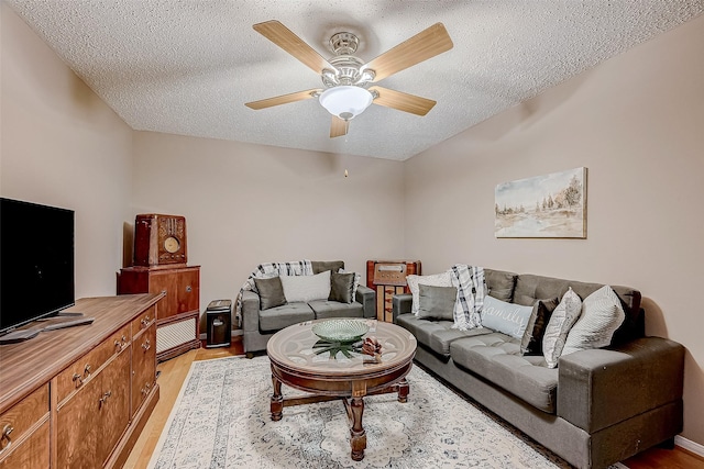 living room featuring a textured ceiling, light hardwood / wood-style floors, and ceiling fan