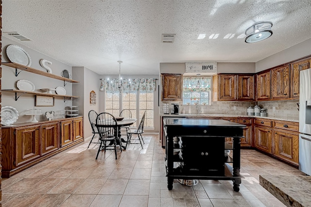 kitchen with decorative backsplash, pendant lighting, a textured ceiling, and an inviting chandelier