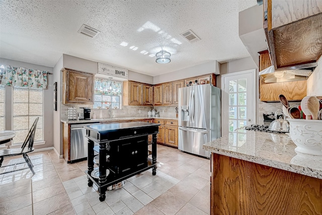 kitchen featuring light tile patterned floors, a textured ceiling, tasteful backsplash, light stone counters, and stainless steel appliances