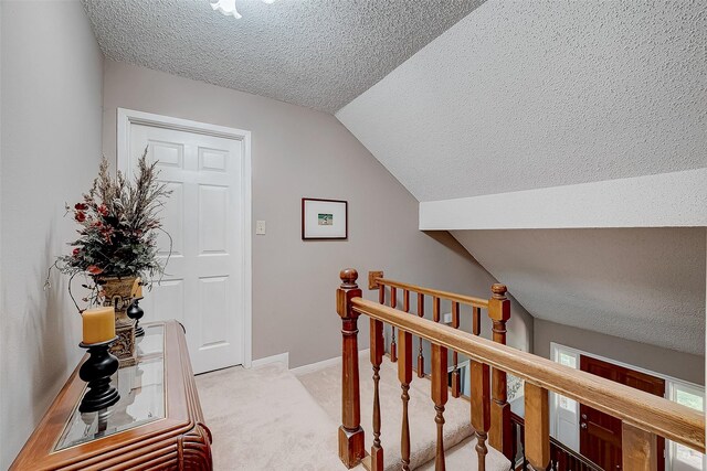 corridor featuring a textured ceiling, light carpet, and lofted ceiling