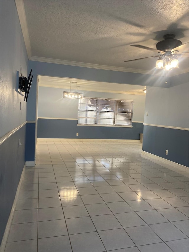 empty room with ceiling fan, ornamental molding, a textured ceiling, and light tile patterned floors