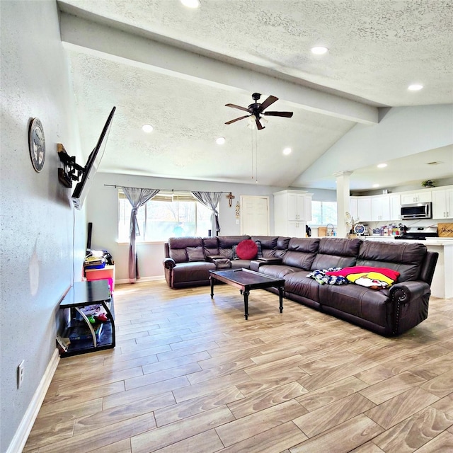 living room featuring a textured ceiling, ceiling fan, and vaulted ceiling with beams