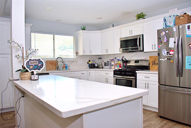 kitchen featuring appliances with stainless steel finishes, light hardwood / wood-style floors, light stone countertops, white cabinets, and sink