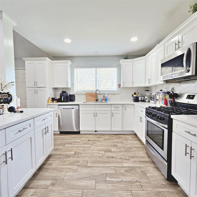 kitchen with appliances with stainless steel finishes, white cabinets, backsplash, and sink